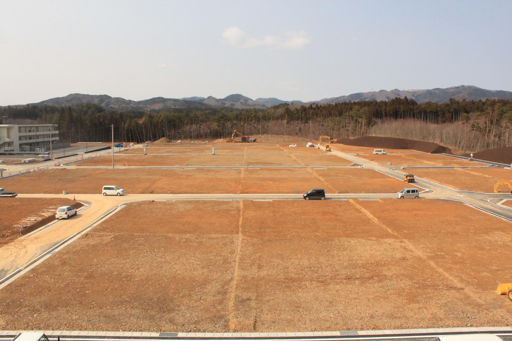 道路の舗装が全体に広がり、車も走っている新しい住宅地の完成間近の写真