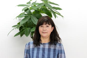 チェック柄の服を着た熊谷さんの写真