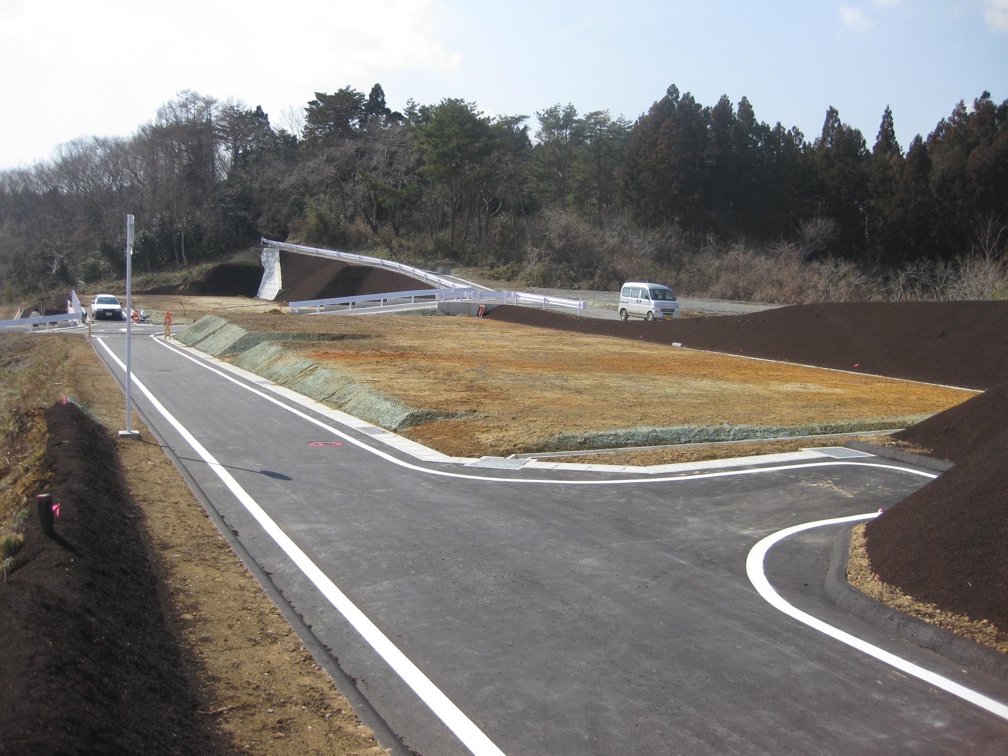 整地されたばかりの分譲地に新しく舗装された道路が伸びる、住宅建設前の風景の写真