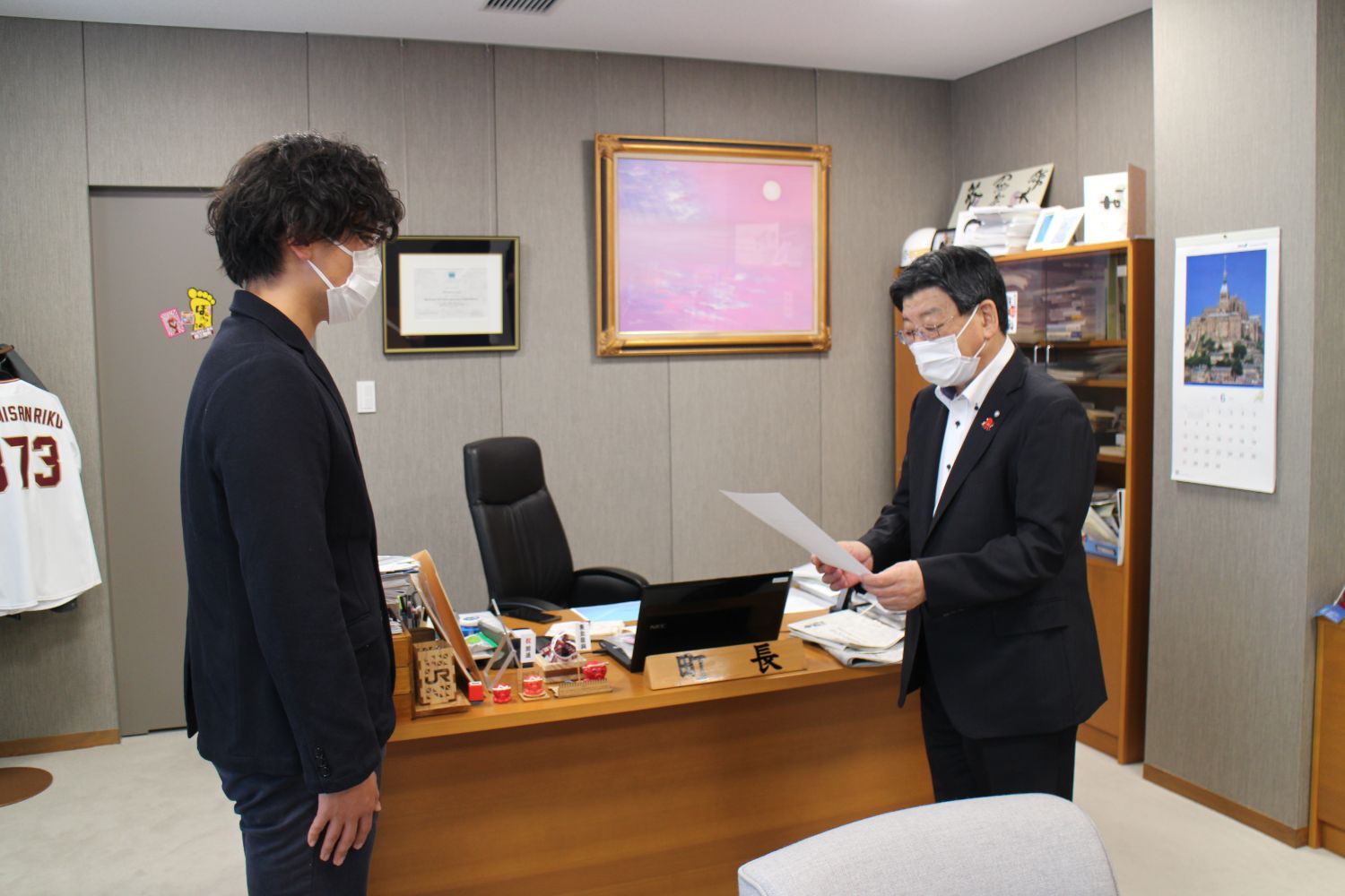 マスクをつけたスーツを着た熊谷さんと南三陸町長が向かい合い、南三陸町長が委嘱状を読み上げている写真