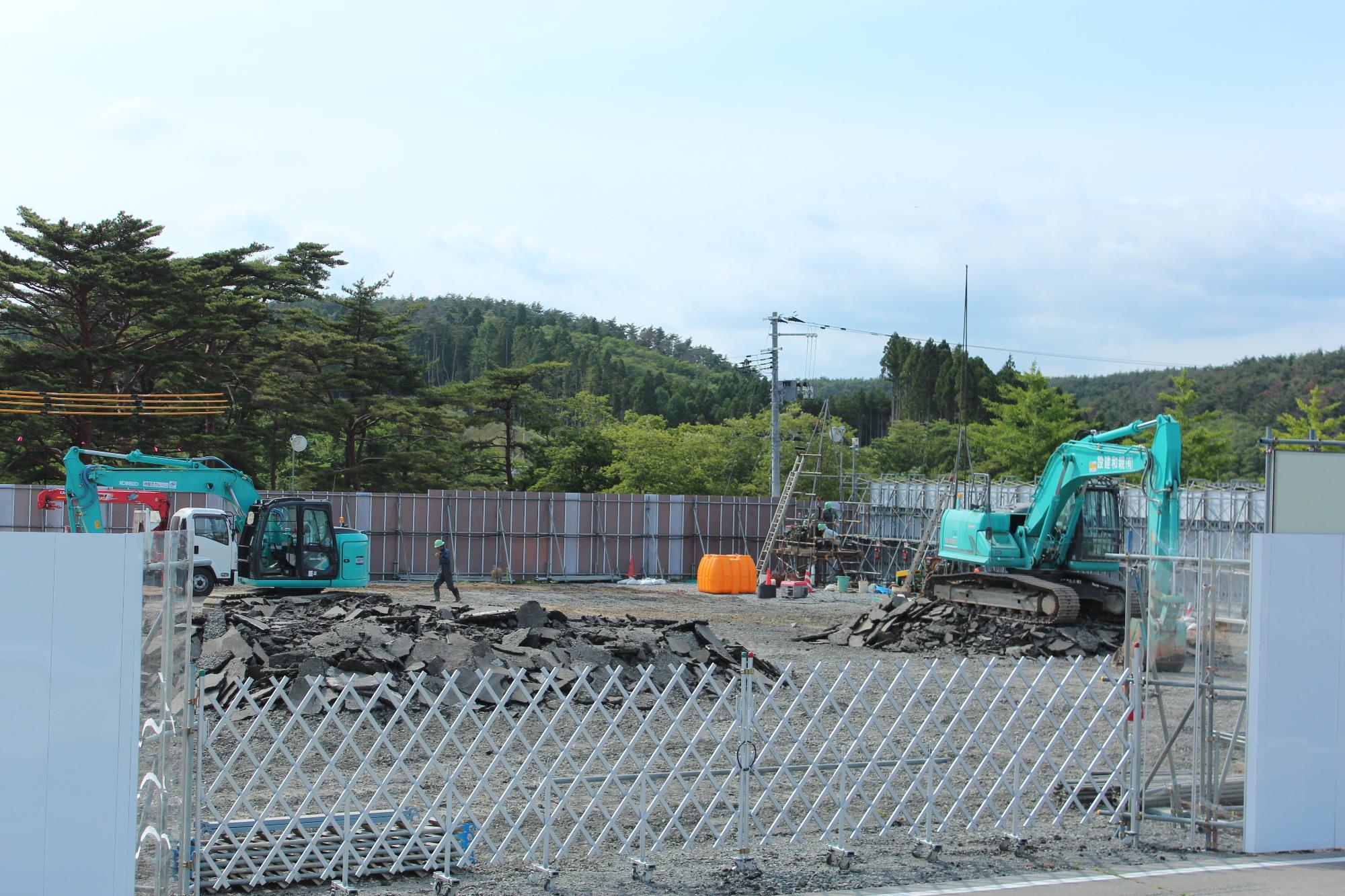 重機で作業員がアスファルトを取り除いている建設現場の初期段階の写真