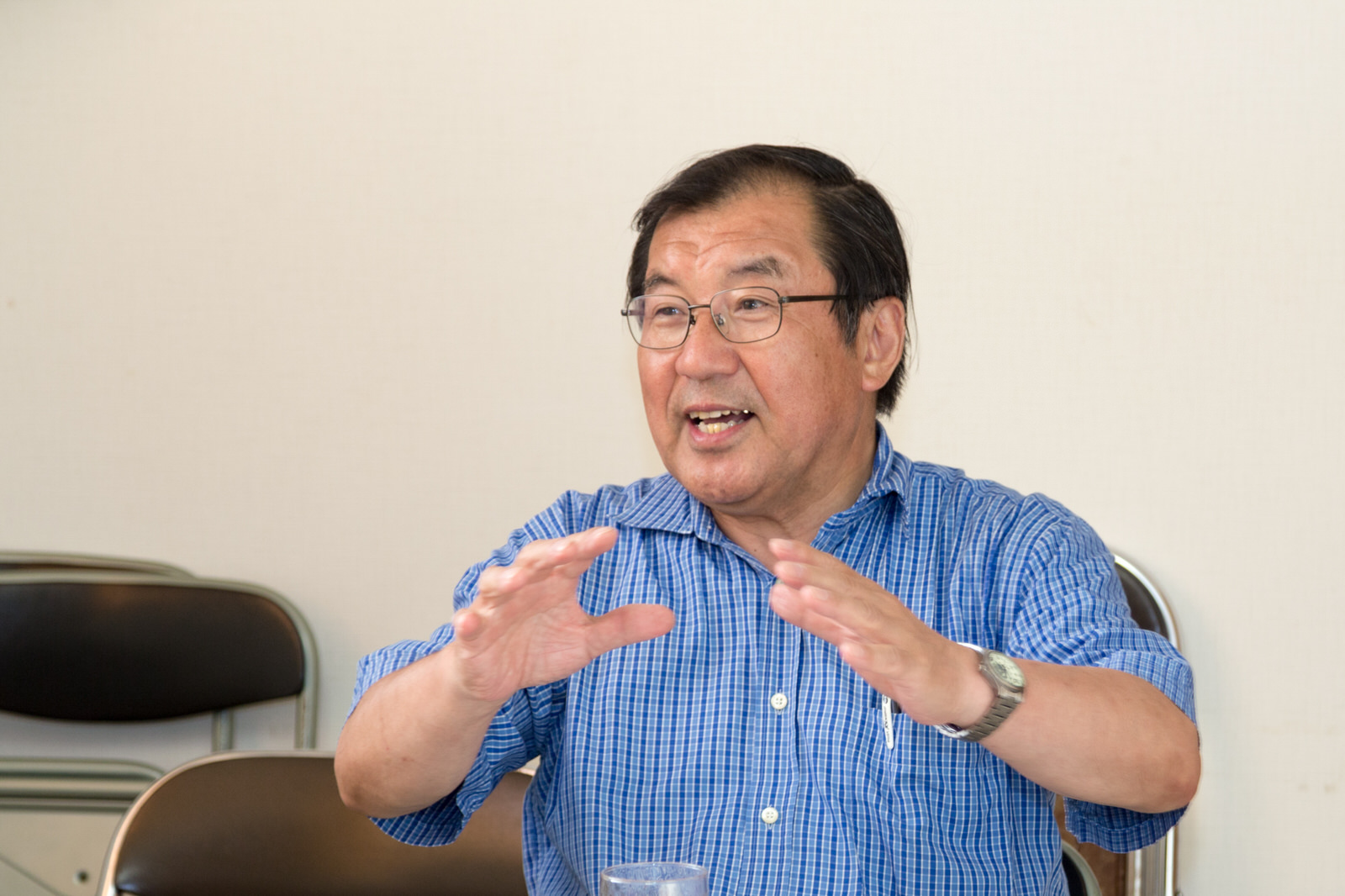 椅子に座り、手振りを交えながら笑顔で話をしている及川さんの写真