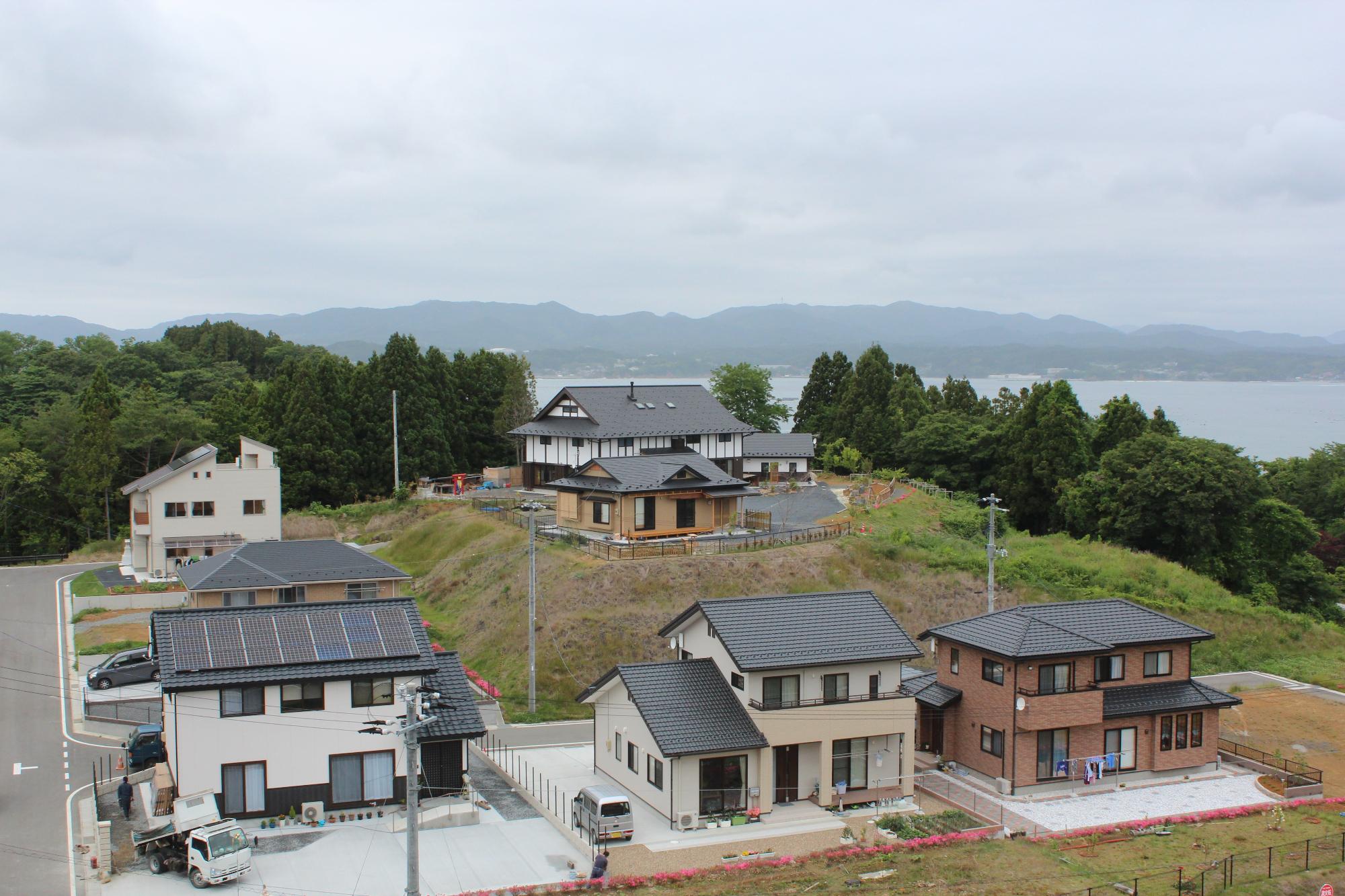 山と海に囲まれた自然豊かな場所に、新しい家々が立ち並ぶ住宅地の写真