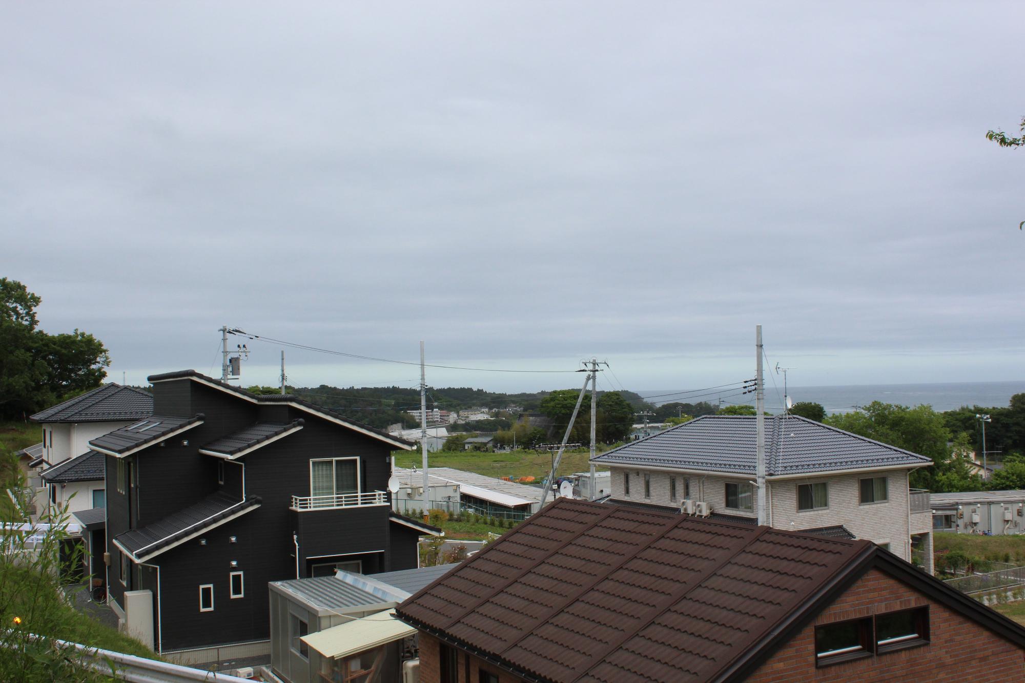 海の見える丘の上に黒や白、茶色の屋根の住宅が整然と並ぶ静かな住宅街の風景の写真
