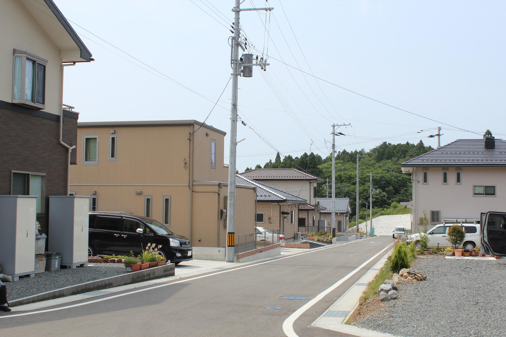 新しく整備された住宅地で、左右に戸建て住宅が立ち並び、中央には舗装された道路が伸びている写真