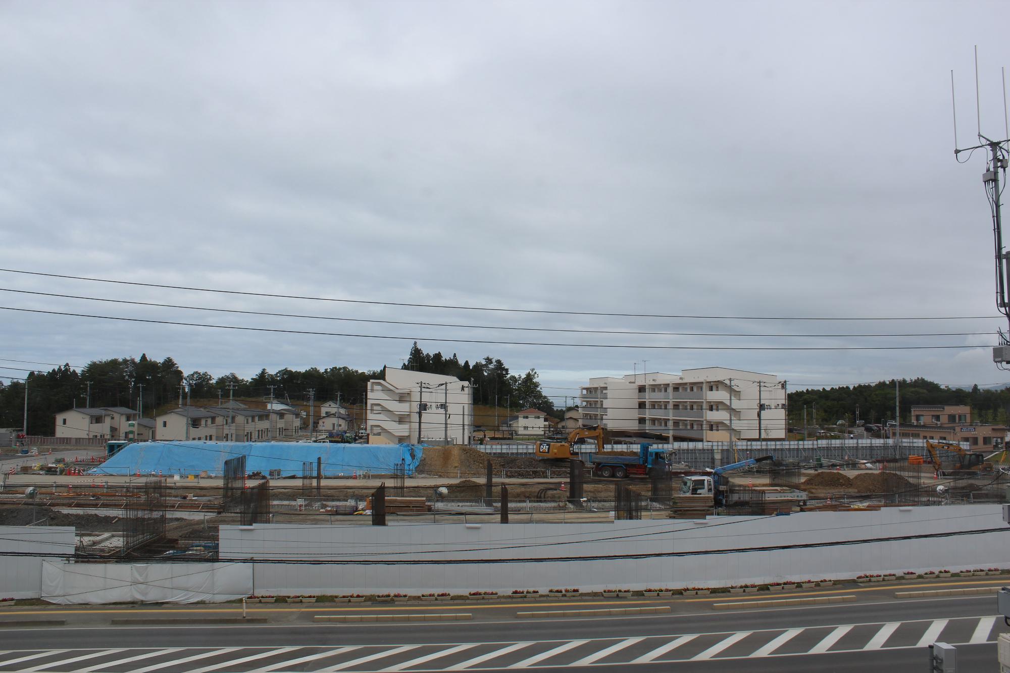 青いシートが斜面にかけられ、多数の鉄骨や建設資材が整然と並べられクレーン車で作業が行われている建設中の平成28年7月5日現在の写真