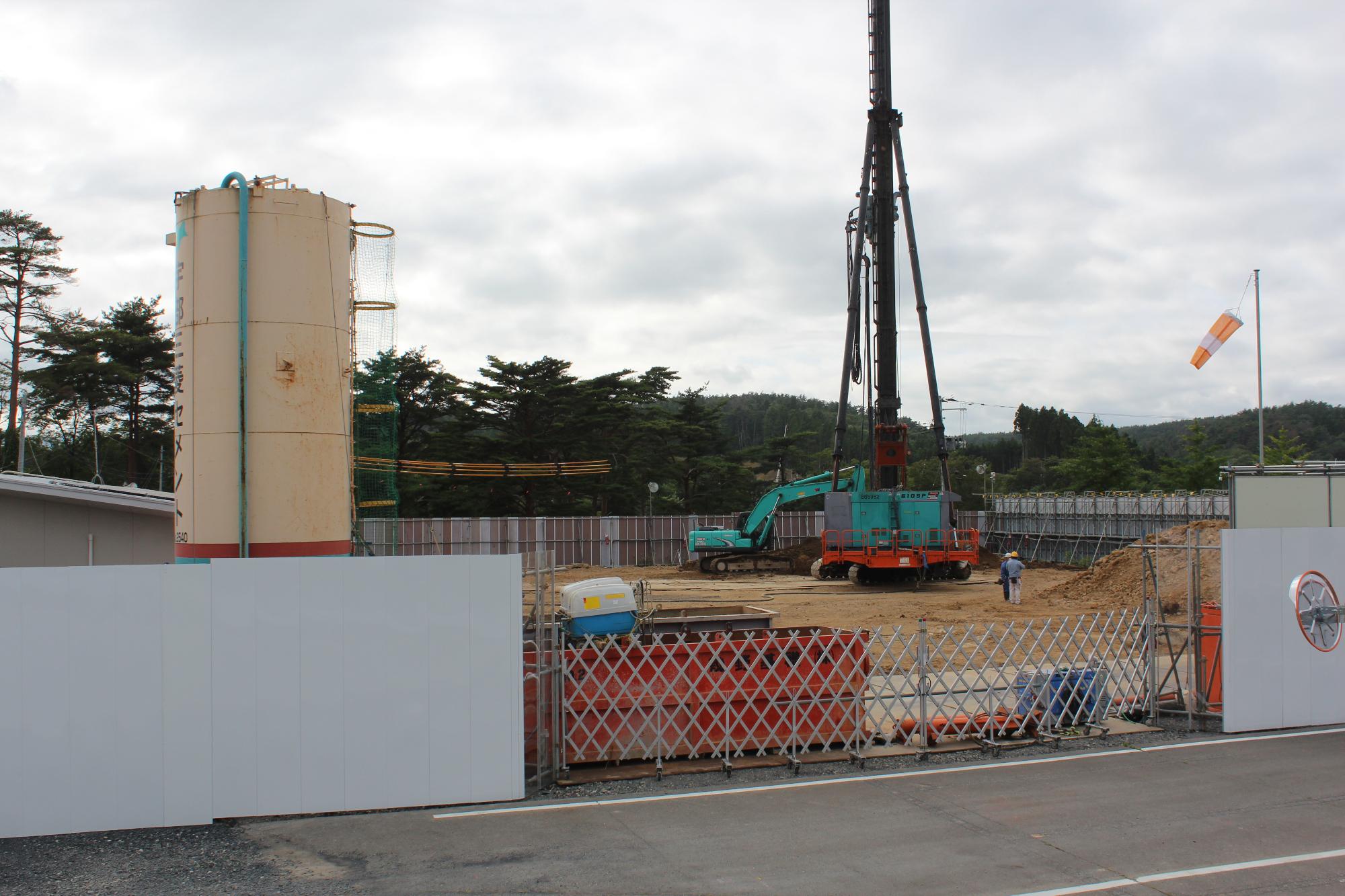 基礎工事のための重機や大きな円筒型の設備がある建設現場の写真