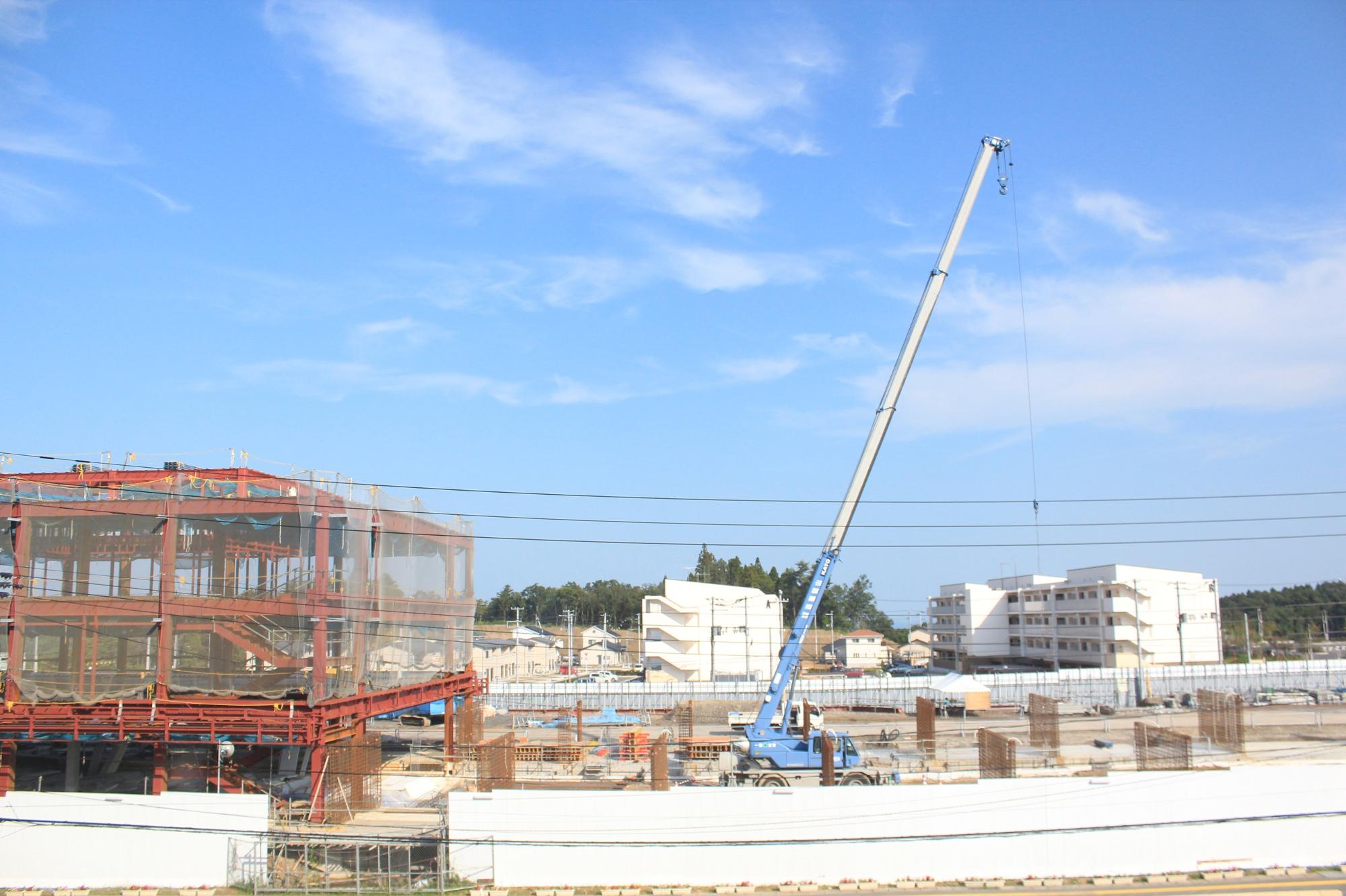 広い敷地には鉄筋が格子状に組まれ、、先端が空高く伸びたクレーン車が稼働している平成28年9月1日現在の写真
