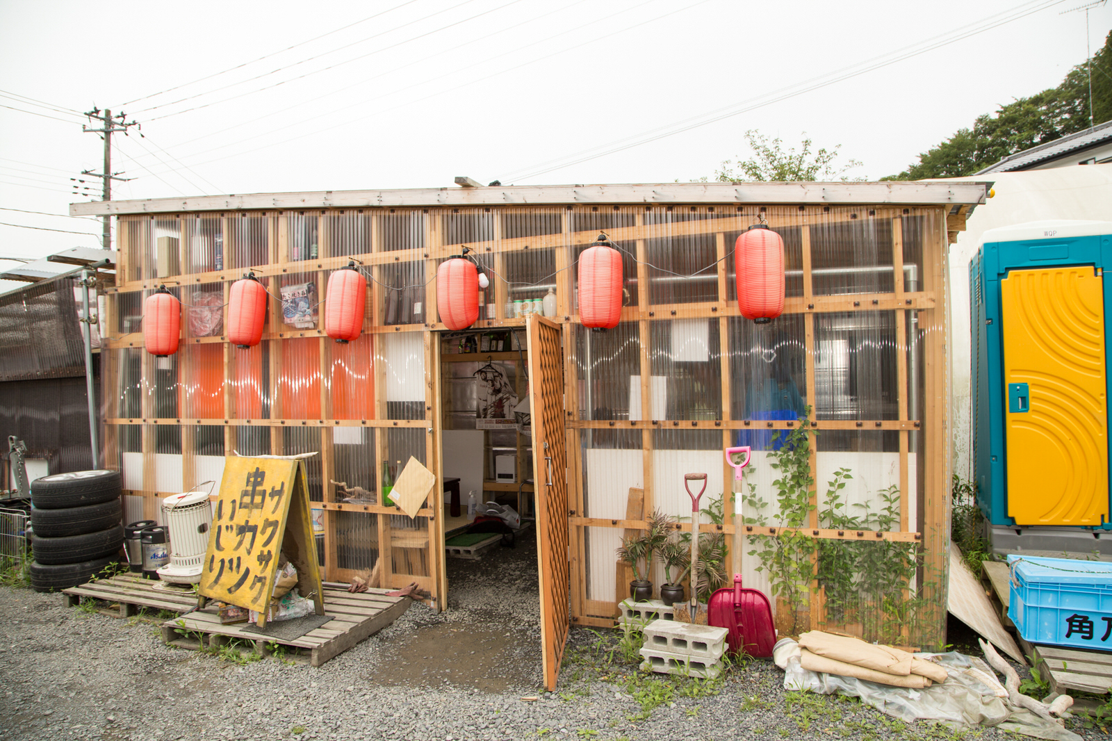 透明の波板で壁が作られた店舗の前の壁に赤ちょうちんが6つ並んで吊るされ、「サクサク串カツいじり」と手書きで書かれた黄色い看板が店の前に置かれている写真