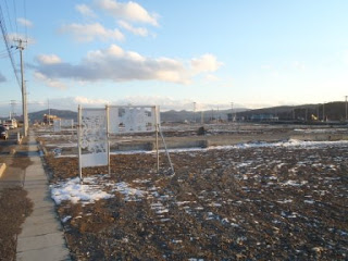 うっすらと雪が積もった広々とした更地が一面に広がり、建物のない静かな風景が広がっている様子の写真