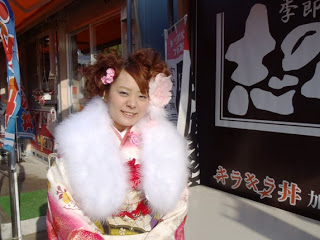 白地にピンクの色があしらわれた振袖を着て、肩に白いショールをかけた艶やかな振袖姿の高橋志乃さんの写真