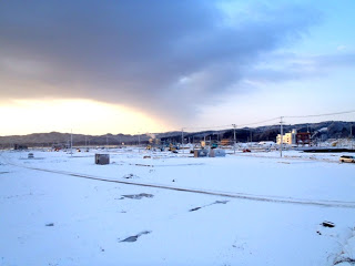 雪に覆われた広い平野が広がり、背景には連なる山々が見える雪景色を写した写真