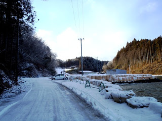 歩道には雪がうっすらと残り、車道は凍結して滑りやすくなっている様子を写した写真