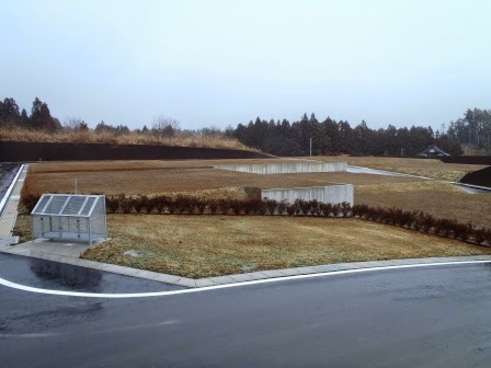 整地された土地に芝生や植栽が施され、ごみの集積所も設置されている写真