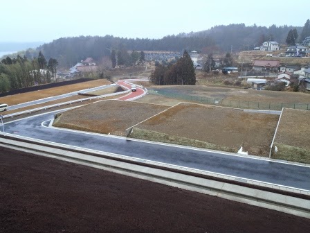 坂道に沿って造成された土地に舗装道路があり、その周囲に家が建てられる予定の区画が並んでいる宅地造成地の写真