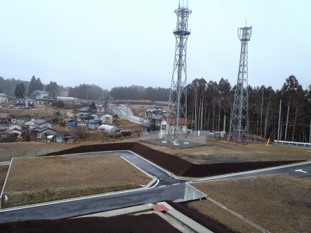 電波塔が立つ造成地の一角から、周辺の既存集落と新しく整地された土地が見渡せる写真