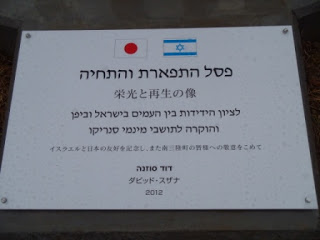 日本とイスラエルの国旗が並んだ白いプレートに「栄光と再生の像」「イスラエルと日本の友好を記念し、また南三陸町の皆様へ敬を込めて」と日本語とイスラエルの言語「ヘブライ語」で文字が書かれている案内版を写した写真