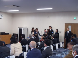 会場に出産を迎えることができた親子が訪れ、関係者の女性が親子を紹介している様子を写した写真