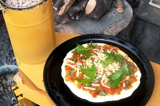 手作りのピザ生地の上にトマトソースやチーズとともに収穫したトウキリーフがトッピングされている様子の写真