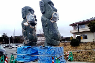 大きなモアイ像の足元が青いブルーシートに覆われて周りを工事用の柵で囲われている写真