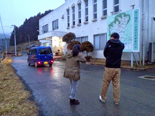 青い車を見送る男女の後姿を写した写真