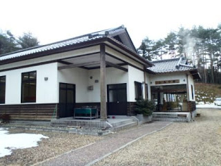 白壁の和風建築の施設が斜め前方から写されたシルク館の外観写真