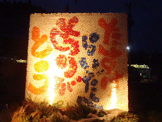 たくさんの白い球体の中に、赤や青の球体「たすけらいだよ ありがとう」のメッセージが描かれた大きな正方形のオブジェがライトアップされている写真