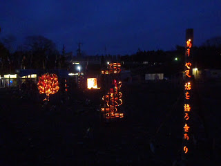 俳句が刻まれた竹灯籠や、複数の竹灯篭を並べて一つのデザインを描いた作品などが夜の広場に並んでいる写真