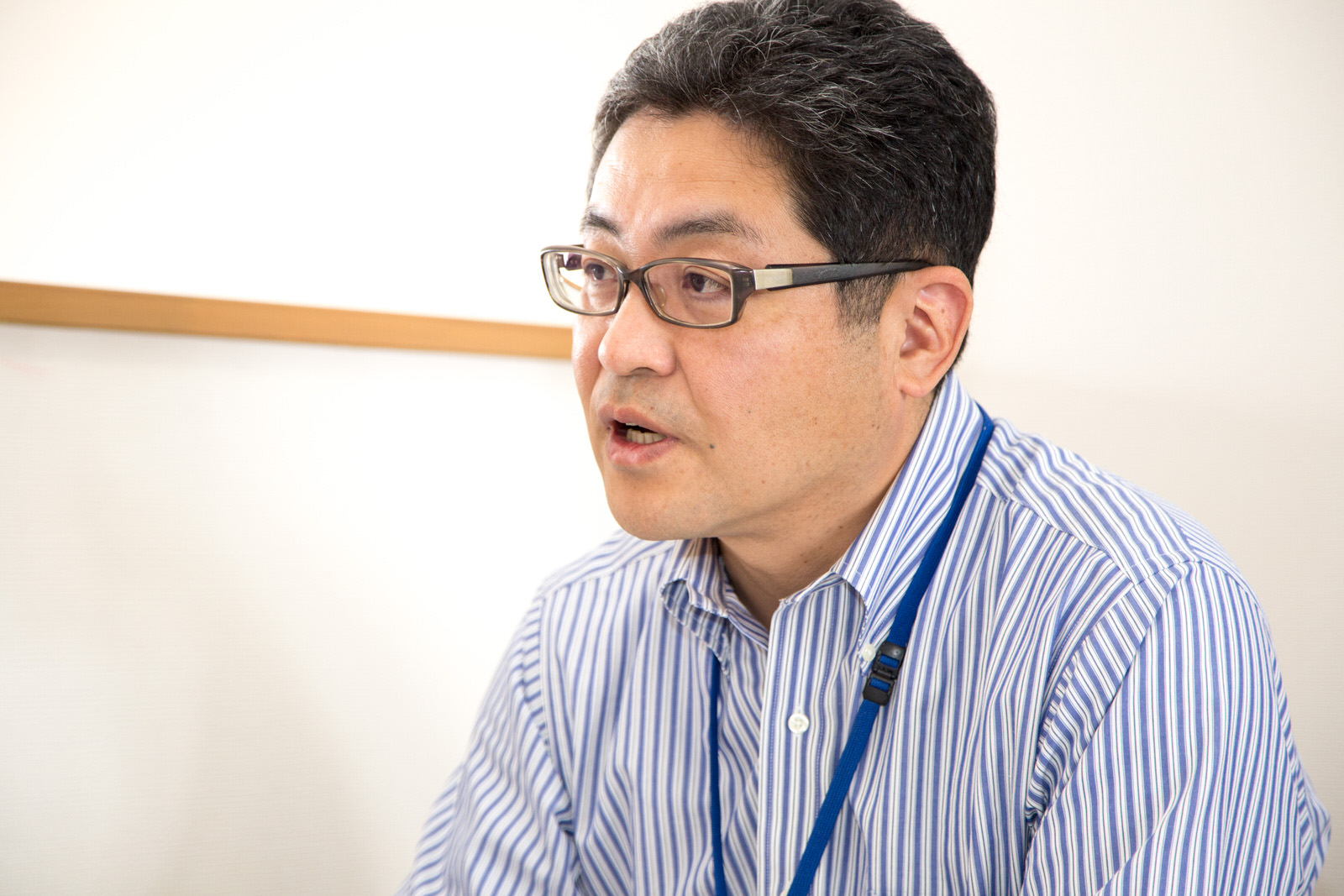 青と白のストライプ柄のシャツを着た千葉課長が、真剣な表情で話しをしている様子をアップで撮影した写真