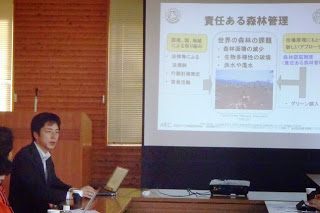 責任ある森林管理について説明しているスライドを指しながらスーツ姿の男性がパソコンを使って発言している写真