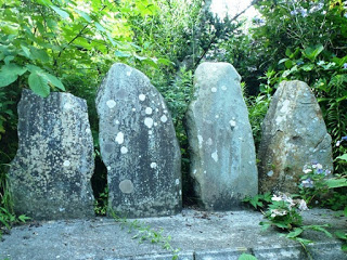 草木の茂る中、古い板碑が4つ横並びに安置されている写真