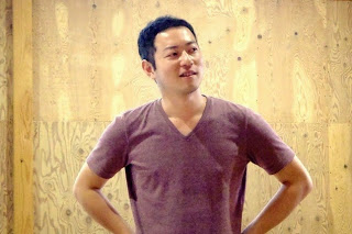 紫色のシャツを着た男性が前に立って、話している様子をアップで撮影した写真