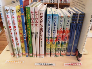 何種類かの本がたてられて並び、手前に「小学校低学年の部」「小学校中学年の部」「小学校高学年の部」と書かれた札が並んでいる写真