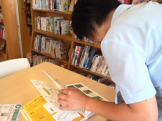 机に置かれた本をめくっている女性の背中を写した写真