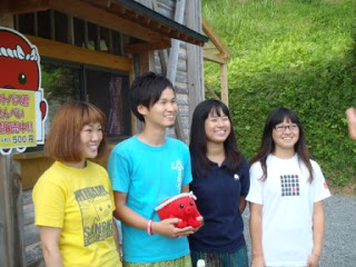 Circle Japanのメンバー4名が屋外で笑顔で並んで立っており、うち1人が赤いオクトパス君のぬいぐるみを持っている様子の写真