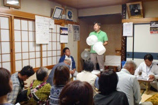 和室の部屋にたくさんの人が参加し前方の男性の説明を聞いている写真