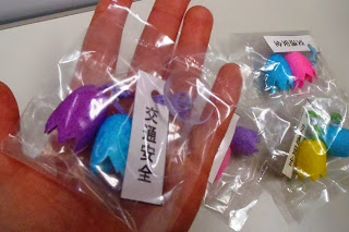 紫色と青色にきれいに染めて作られた繭の交通安全マスコットが透明なビニール袋に梱包されている写真