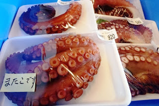 茹でたタコの足が、白いトレイに一つずつ丁寧にパック詰めされて売られている写真