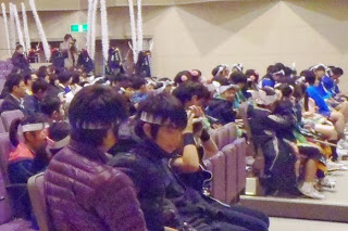 観客席ではちまきを付けた出演者と思われる子どもたちや保護者たちがくつろいでいる様子を写した写真