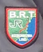 「B.R.T」の文字とJRのロゴが赤い線が描かれた地図の上にデザインされた、制服のエンブレムのアップ写真