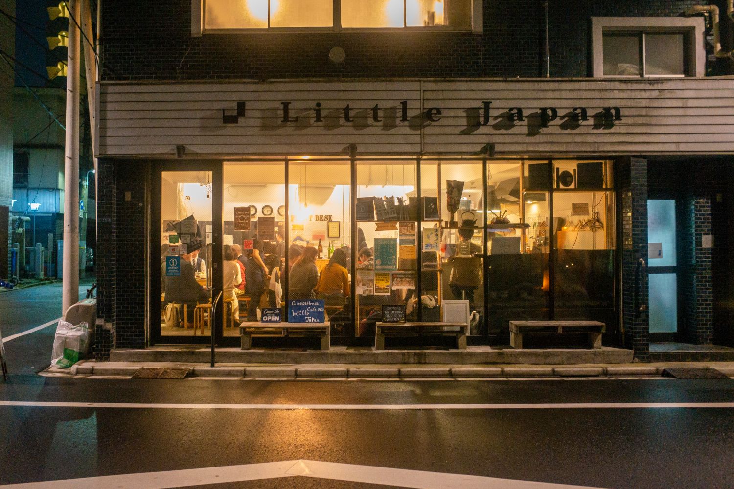 夜の街角の店内で多くの参加者達が食事を楽しむ様子をガラス越しに撮影した写真