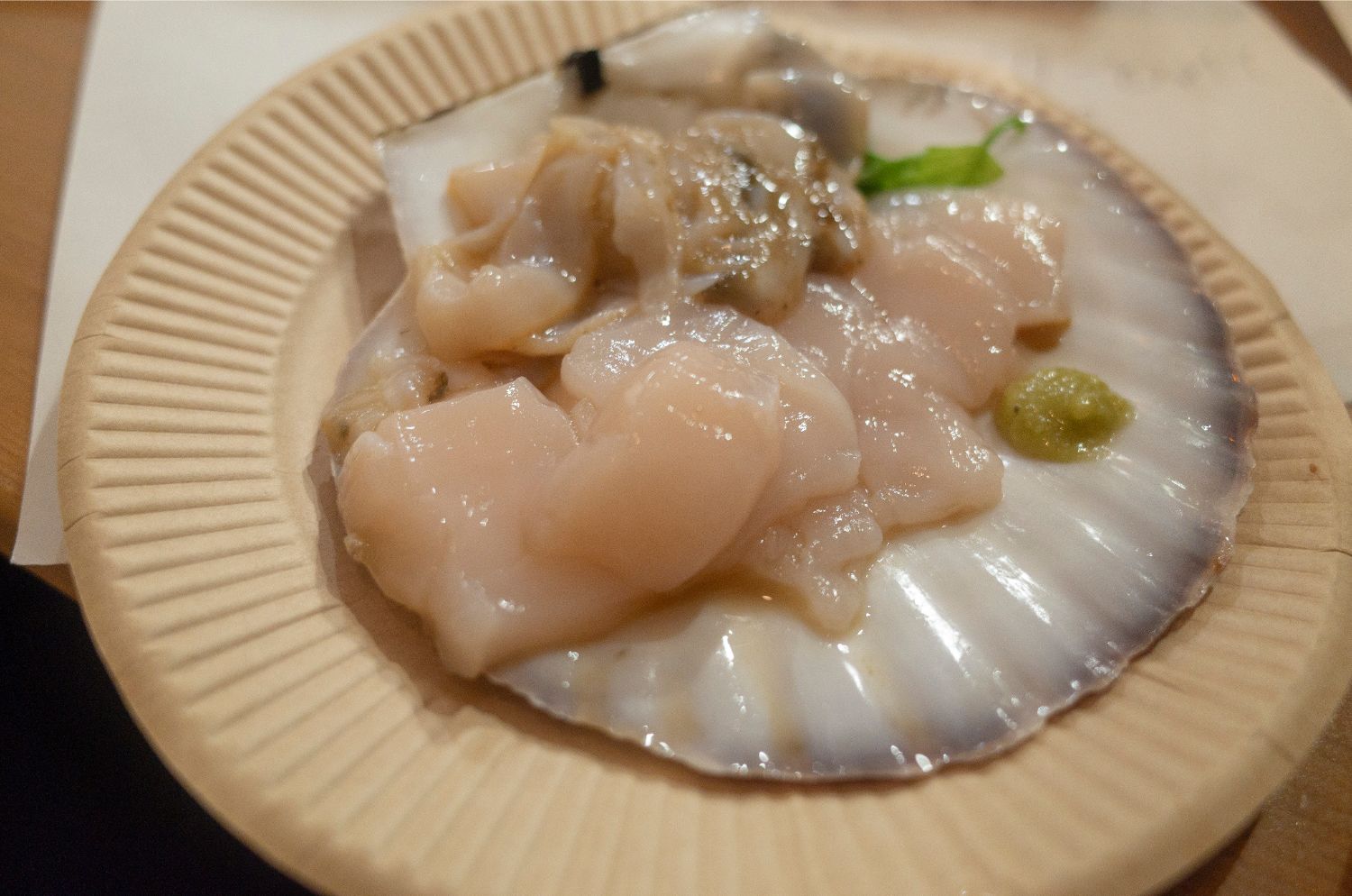 ホタテの貝の上にワサビが添えられたホタテの刺し身の写真