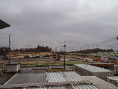 広大な整地された土地に工事用車両や資材が配置されており、開発が進む様子が見て取れる工事現場の全景の写真