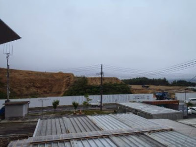 白い工事用フェンスと土がむき出しになった盛土の斜面が広がり、進行状況が確認できる造成地の一部の写真