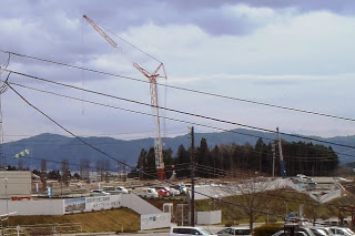 山並みが広がっている手前の建設現場に大きなクレーンが立ち工事が行われている写真