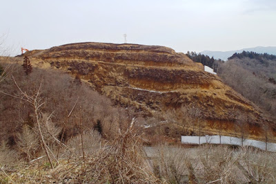 木が伐採され、重機で山が段々に削られた茶色の地肌が露出している造成工事中の様子の写真