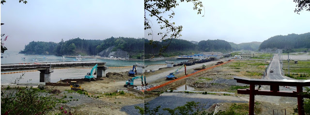 鳥居の前に道路が通り左側の入り江の岸辺には複数の大型ショベルカーが作業をし、橋の一部分が残っている復旧作業の写真