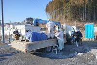 作業服を着た数人の男性が、トラックの荷台でモアイ像を荷造りしている様子を写した、運搬準備の写真