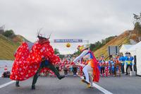 高速道路の開通式で伝統的な衣装を着た人たちが踊りを披露している写真