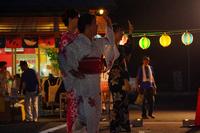 白やピンク色などの浴衣姿の女性たちが左手を上げて盆踊りを踊っている様子の写真